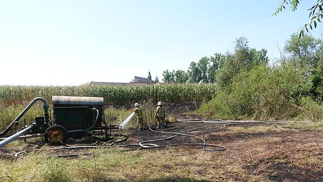 Bei Mariaburghausen brannte es am Samstag auf freier Fläche. Die Polizei vermutet, dass an einem Wasserpumpenwagen (links)  das Feuer entstanden ist. Unser Bild entstand während des Einsatzes der Feuerwehr; im Hintergrund ist die ehemalige Klosterkirche von Mariaburghausen zu sehen. Feuerwehr Haßfurt
