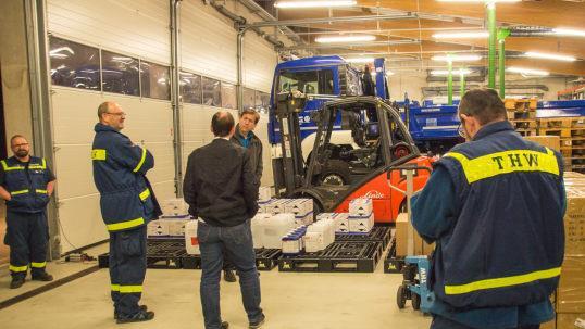 MdL Michael Hofmann (3. v. r.) hatte für den Landkreis weitere 22.000 Masken beschafft und war bei der Ankunft dabei. Auch Landrat Hermann Ulm (2. v. r.) verschaffte sich einen Überblick über den Bestand im Lager, das von Helfern des THW Kirchehrenbach betreut wird. Foto: Karoline Kötter, THW