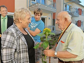 Mit Ernst Hofmann (rechts ) hält die Stimmung Einzug im neuen AWO-Serniorenzentrum. Zur Begrüßung gibt's eine Sonnenblume von Fachbereichsleiterin Gundi Heusinger. Geschäftsführer Werner Dippold (links)begrüßt die ersten Bewohner persönlich. Foto: Ronald Rinklef
