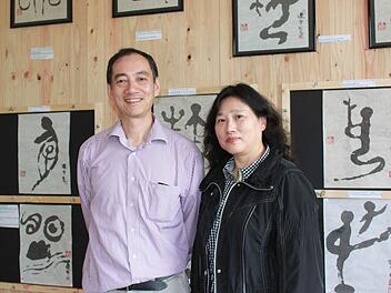 Xiao Dan Xue und Xing Wang vor ihren historischen Schriftzeichen. Zu jedem Bild haben sie eine Erklärung, wie das Zeichen sich weiterentwickelt hat und heute aussieht. Foto: Katharina Becht