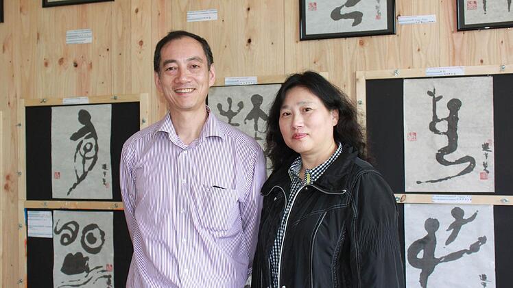 Xiao Dan Xue und Xing Wang vor ihren historischen Schriftzeichen. Zu jedem Bild haben sie eine Erklärung, wie das Zeichen sich weiterentwickelt hat und heute aussieht. Foto: Katharina Becht