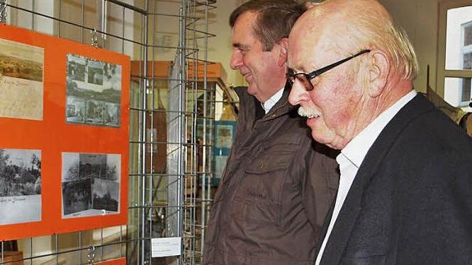 Die beiden Schönsreuther Heinz Anders und Peter Hofmann (von rechts) betrachten eine Wandtafel mit Fotos von ihrem Heimatort. Fotos: Alfred Thieret