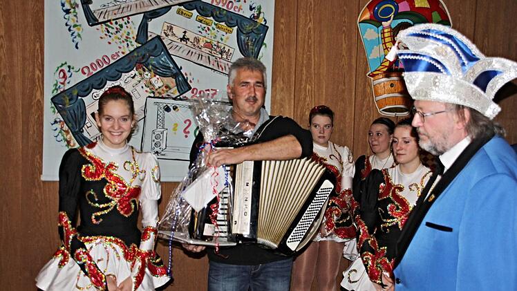 Stefan Wolfschmidt (mit Schifferklavier) wurde besonders geehrt und mit einem Präsent bedacht. Über Jahrzehnte ist er beim Fasching in Ebern eine feste Größe. Rechts 2. Vorsitzender Walter Ullrich und links Gardemädchen Kathrin Habermann. Foto: Helmut Will