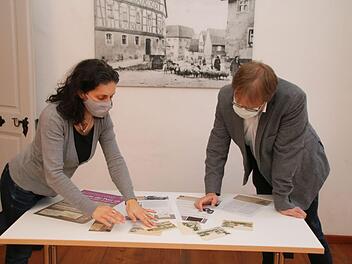 Christine Schikora und Ortwin Guhling betrachten im Heimatspielhaus die Entwürfe der Schautafeln und die alten Ansichtskarten. Vom 17. Oktober bis zum 8. November ist die Ausstellung über 235 Jahre Münnerstädter Postgeschichte zu sehen. Foto: Thomas Malz