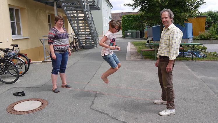 Bea Wirth steht mit Martin Vogel beim "Gummihupf" für ihre Tochter Svea. Die "Ferienmacher" wollen das alte Spiel wieder bekannt machen.   Fotos: Lindner