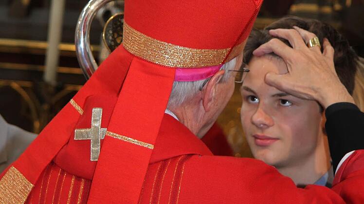 Erzbischof Ludwig Schick zeichnet den Firmlingen mit Chrisamöl das Kreuz auf die Stirn. Foto: Sonny Adam