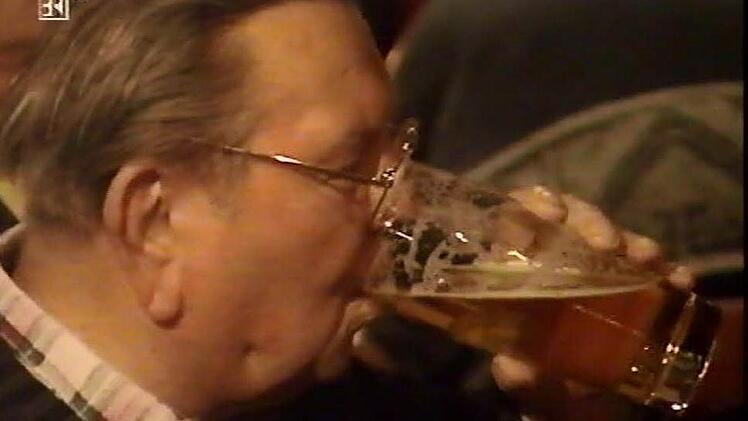 Heinz Knörrer (†) schluckt sein geliebtes Mönchshof Original aus dem Willibecher. Selbst ein Original, summt er meist vergnügt vor sich hin: "Schrumm, schrumm, schrumm, wer ärbert, der is dumm." Screenshot: BR