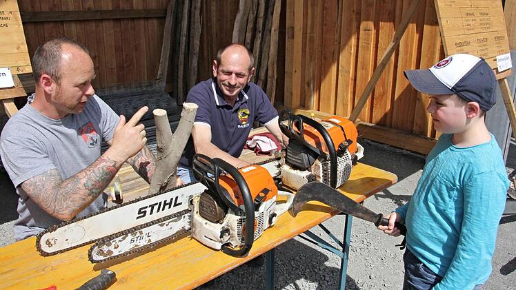 Recht bedrohlich wirkt der achtjährige Luan aus Steinberg bei Kronach mit einem Werkzeug für Jungholzpflege in der Hand, der sich vom Holzunternehmer Thomas Birklein und dem städtischen Waldarbeiter Thomas Holzheid (von links) erklären lässt, was im Wald mit Motorsägen alles gemacht wird. Foto: Helmut Will