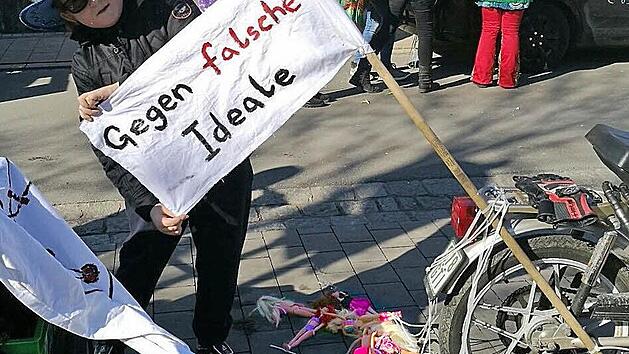 Ein Mitglied des Vereins Rollsport-Freunde Forchheim pr&auml;sentiert kurz vor dem Start des Umzuges eine Seite des Banners. Zum &Auml;rgernis wurde dann aber die R&uuml;ckseite des Banners und die hinter dem Mofa hergeschleiften Barbiepuppen. Foto: Rollsport-Freunde Forchheim
