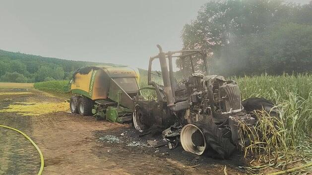 Bei Hirschaid im Landkreis Bamberg ist am Sonntagabend (9. Juli) ein Traktor mit Ballenpresse in Brand geraten. Das Gespann brannte völlig aus und das Feuer breitete sich auf ein anliegendes Feld aus. 60 Feuerwehrleute waren bei der Löschung im Einsatz, zwei haben sich dabei verletzt. Foto: Georg Kalb