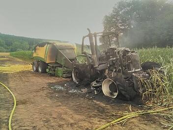 Bei Hirschaid im Landkreis Bamberg ist am Sonntagabend (9. Juli) ein Traktor mit Ballenpresse in Brand geraten. Das Gespann brannte völlig aus und das Feuer breitete sich auf ein anliegendes Feld aus. 60 Feuerwehrleute waren bei der Löschung im Einsatz, zwei haben sich dabei verletzt. Foto: Georg Kalb