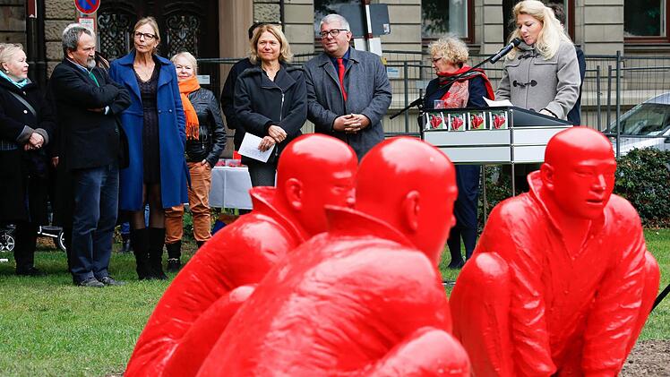 Fiona Freifrau von Colberg am Rednerpult, das neben den hockenden roten Männern mitten in der Grünanlage stand.Foto: Matthias Hoch