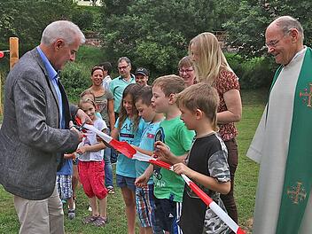 Bürgermeister Jürgen Karle durchschneidet symbolisch das Absperrband des neugestalteten Spielplatzes. Die Mädchen und Jungen warten schon ganz ungeduldig. Foto: Gerd Schaar