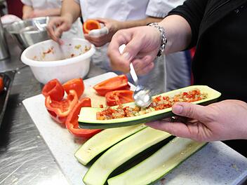 Die Teilnehmer füllen die Zucchini, Tomaten und Paprika. Foto: Cathérine Sykosch