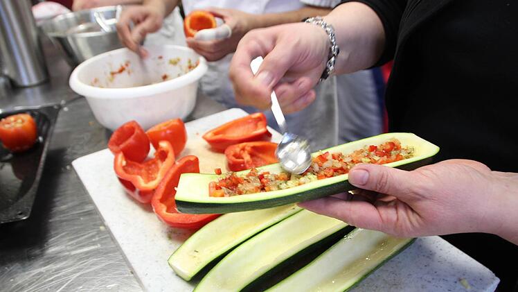 Die Teilnehmer füllen die Zucchini, Tomaten und Paprika. Foto: Cathérine Sykosch