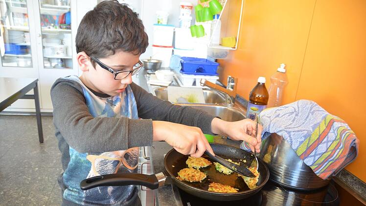 Riad wendet die Pastinakenküchlein in der Pfanne.