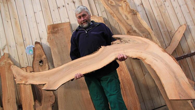 Hans-Karl Hertel mit einem kurios geformten Apfelbaum-Brett, das zum Beispiel mit LED-Leuchten bestückt zum Blickfang einer Wohnung werden kann. Seine eigene gute Stube in Horsdorf hat er mit vielen Holzornamenten stilvoll ausgestattet. Foto: Matthias Einwag