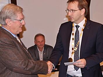 Händedruck und Urkunde vom Sohn: Werner Thein, ehemaliger Bürgermeister in Maroldsweisach (links), erhält von seinem Sohn Wolfram, Bürgermeister der Marktgemeinde, die Dankurkunde des Freistaates Bayern.  Helmut Will