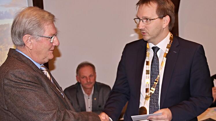 Händedruck und Urkunde vom Sohn: Werner Thein, ehemaliger Bürgermeister in Maroldsweisach (links), erhält von seinem Sohn Wolfram, Bürgermeister der Marktgemeinde, die Dankurkunde des Freistaates Bayern.  Helmut Will