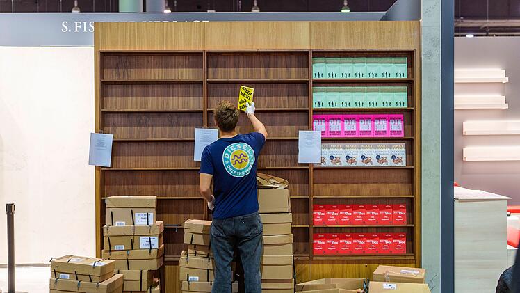 Ein junger Mann r&auml;umt B&uuml;cher in ein Regal ein