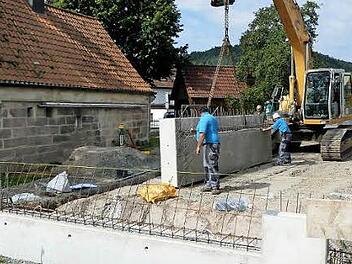 Mit dem Bagger wird das nächste Fertigbauteil in die Baugrube eingepasst. Foto: Dieter Hübner