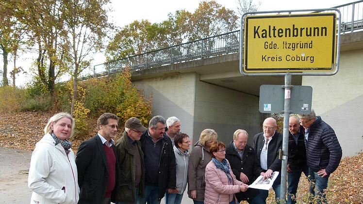 Dieter Scherbel (Dritter von rechts) und Bürgermeister Werner Thomas (Vierter von rechts) erläutern die Pläne der Zufahrt zum Neubaugebiet "Kapellenfeld" durch den Brückenneubau. Foto: Lothar Weidner