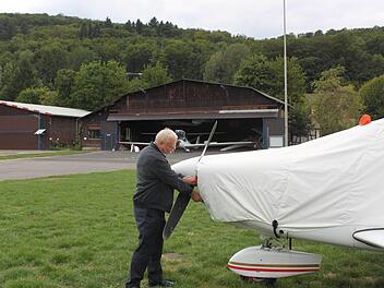 Bernd Strauß und die mit Planen abgedeckte Maschine der Motorflieger. Im Hintergrund ist der alte Hangar zu sehen. Foto: Thomas Mäuser