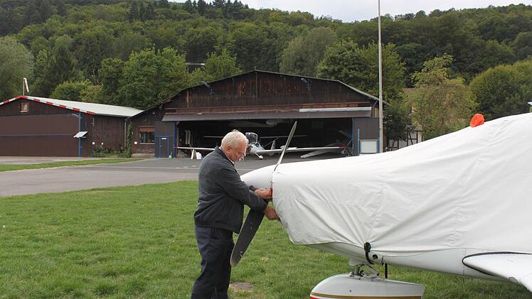 Bernd Strauß und die mit Planen abgedeckte Maschine der Motorflieger. Im Hintergrund ist der alte Hangar zu sehen. Foto: Thomas Mäuser