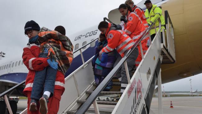 Die Kinder aus Angola werden von den Helfern die Gangway hinuntergetragen. Foto: BRK-Medienteam