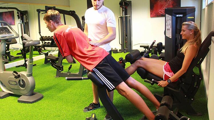 Tim Weimann (links) und Leni Schneider (rechts) testen schon einmal den neuen Fitness-Raum. Lorenz Beck (Mitte) kontrolliert die Haltung, damit die Übungen richtig ausgeführt werden. Foto: Carmen Schmitt