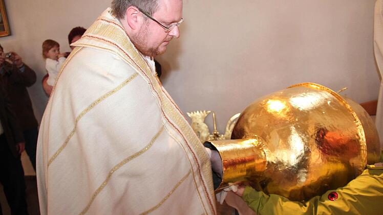 Pfarrer Thomas Ringer schiebt die Kapsel in die goldene Kugel.