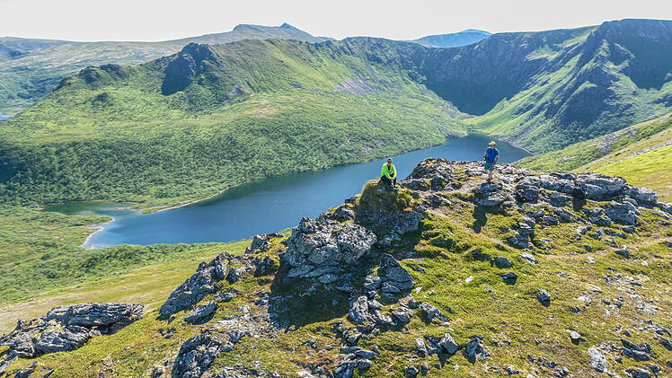aerial, bird view 2 caucasian hikers on Laupen mountain during summer, village bleik, beach, mountains in background. Bleikmorenen nature reserve Vester&aring;len, vesteralen islands Beautiful hiking destin