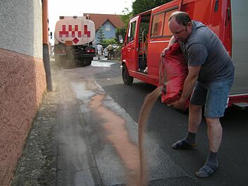 Matthias Eichenmüller von der Feuerwehr schüttet Ölbindemittel auf die verunreinigte Straße. Foto: Peter Seufert