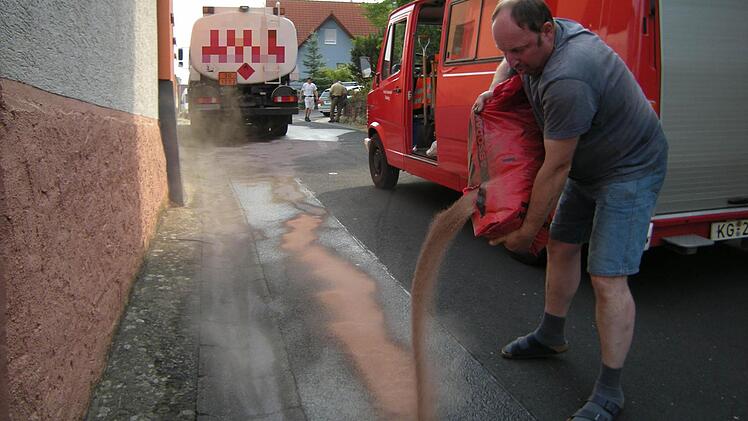 Matthias Eichenmüller von der Feuerwehr schüttet Ölbindemittel auf die verunreinigte Straße. Foto: Peter Seufert