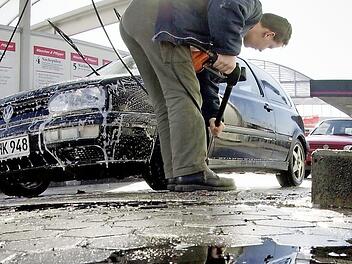 Ein Mann befreit sein Auto vom Winterschmutz. Foto: dpa