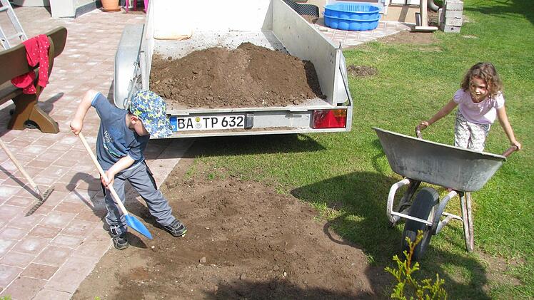 Die vierjährige Simona und ihr Cousin Fabian (drei Jahre) machen sich unentbehrlich beim Aufräumen des Gartens.