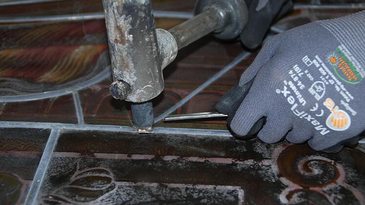 Mit dem Lötkolben wird das Bleinetz aufgearbeitet. Foto: Glasmalerei Peters
