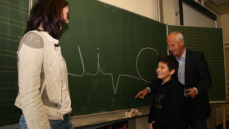 Muhanad Eiz Eddin zeigt Schulleiter Michael Pfitzner und Lehrerin Stephanie Leutheußer, wie sein Name in arabischer Schrift aussieht. Foto: Matthias Beetz