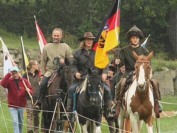 Einmarsch der Teilnehmer zur deutschen Meisterschaft im berittenen Bogenschießen auf dem Hummelhof in Trossenfurt mit Pferden und Fahnen.