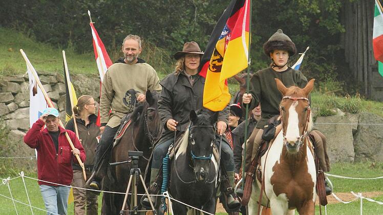 Einmarsch der Teilnehmer zur deutschen Meisterschaft im berittenen Bogenschießen auf dem Hummelhof in Trossenfurt mit Pferden und Fahnen.