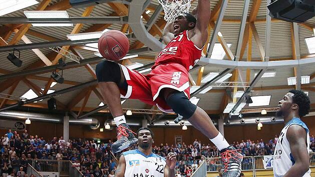 Mit diesem wuchtigen Dunking machte Bambergs Topwerfer Trevor Mbakwe (19 Punkte) den Hunderter f&uuml;r die Brose Baskets voll. Die Crailsheimer Stevie Johnson (l.) und Josten Crow sind machtlos. Fotos: Daniel L&ouml;b