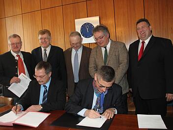 Die Bürgermeister von Bad Berneck und Neuenmarkt, Jürgen Zinnert (links) und Siegfried Decker, unterzeichnen die Urkunde für die Erstellung eines gemeinsamen Energiekonzepts. Mit im Bild (hinten, von links) Wolfgang Böhm von der Energieagentur Nordbayern, Goldkronachs Bürgermeister Günter Exner, sein Marktschorgaster Kollege Hans Tischhöfer, Hans Rainer Albart vom Amt für ländliche Entwicklung in Bamberg und Himmelkrons Bürgermeister Gerhard Schneider. Foto: Jürgen Gärtner