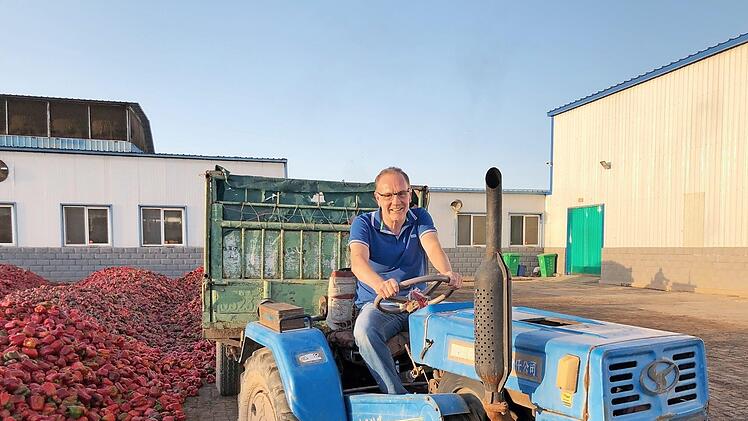 Christoph Mix setzt sich in China auf dem Hof eines Paprika-Lieferanten selbst auf den Traktor.