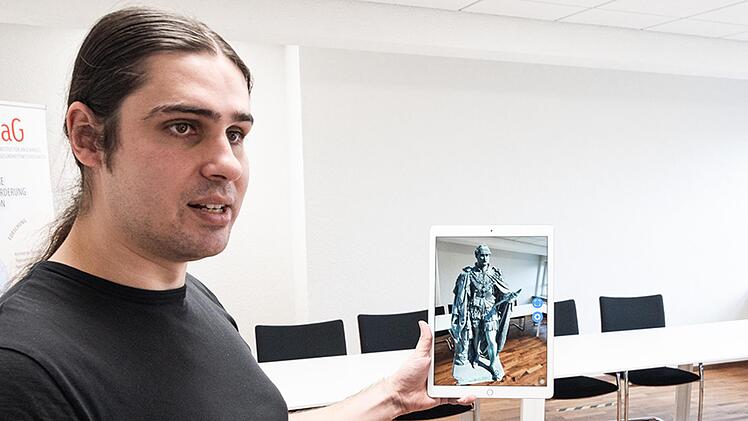 Mit der Kamera des Tablets erfasst Daniel Schneider von der Hochschule Coburg den Raum und kann dabei virtuell Objekte wie das Albertdenkmal platzieren.  Foto: Julian Uebe, Hochschule Coburg