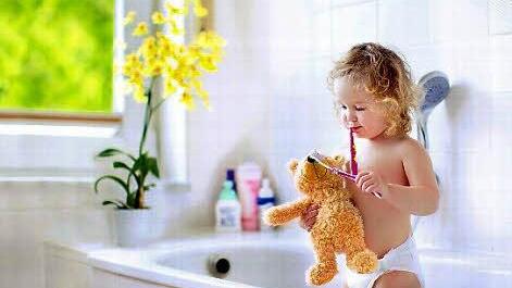 Johanna will unbedingt dem Bären die Zähne putzen - im kindgerechten Bad ist das kein Problem.  Foto: Vereinigung Deutsche Sanitärwirtschaft (VDS) / Shutterstock / FamVeld
