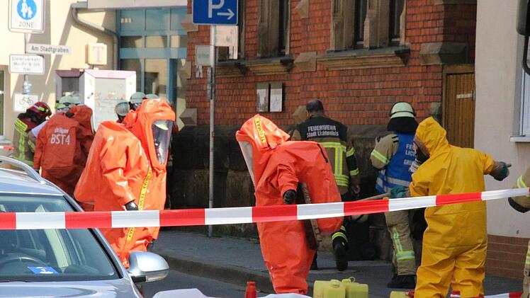 Ein Feuerwehrmann reinigt die Chemieschutzanzüge zweier Kollegen am Dienstag nach dem Einsatz in dem von Ammoniakgas verseuchten Keller.