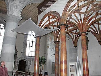 Stadtpfarrer Pater Markus begutachtet die beiden Netze, die derzeit zu Testzwecken in der Kirche hängen. Das grobmaschige, weniger auffällige Netz (rechts) soll demnächst im Kirchenschiff gespannt werden, damit kein lockerer Putz auf Kirchenbesucher fallen kann. Fotos: Heike Beudert