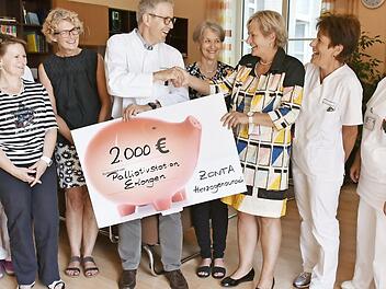 Prof. Ostgathe nimmt den Spendenscheck von Jutta Rost vom Zonta-Club im Wohnzimmer der Palliativstation entgegen.  Foto: Uni-Klinikum Erlangen