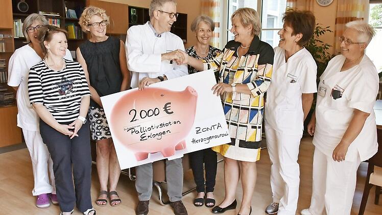 Prof. Ostgathe nimmt den Spendenscheck von Jutta Rost vom Zonta-Club im Wohnzimmer der Palliativstation entgegen.  Foto: Uni-Klinikum Erlangen