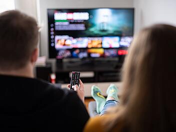Paar sitzt vor einem Fernseher mit Streamingdiensten